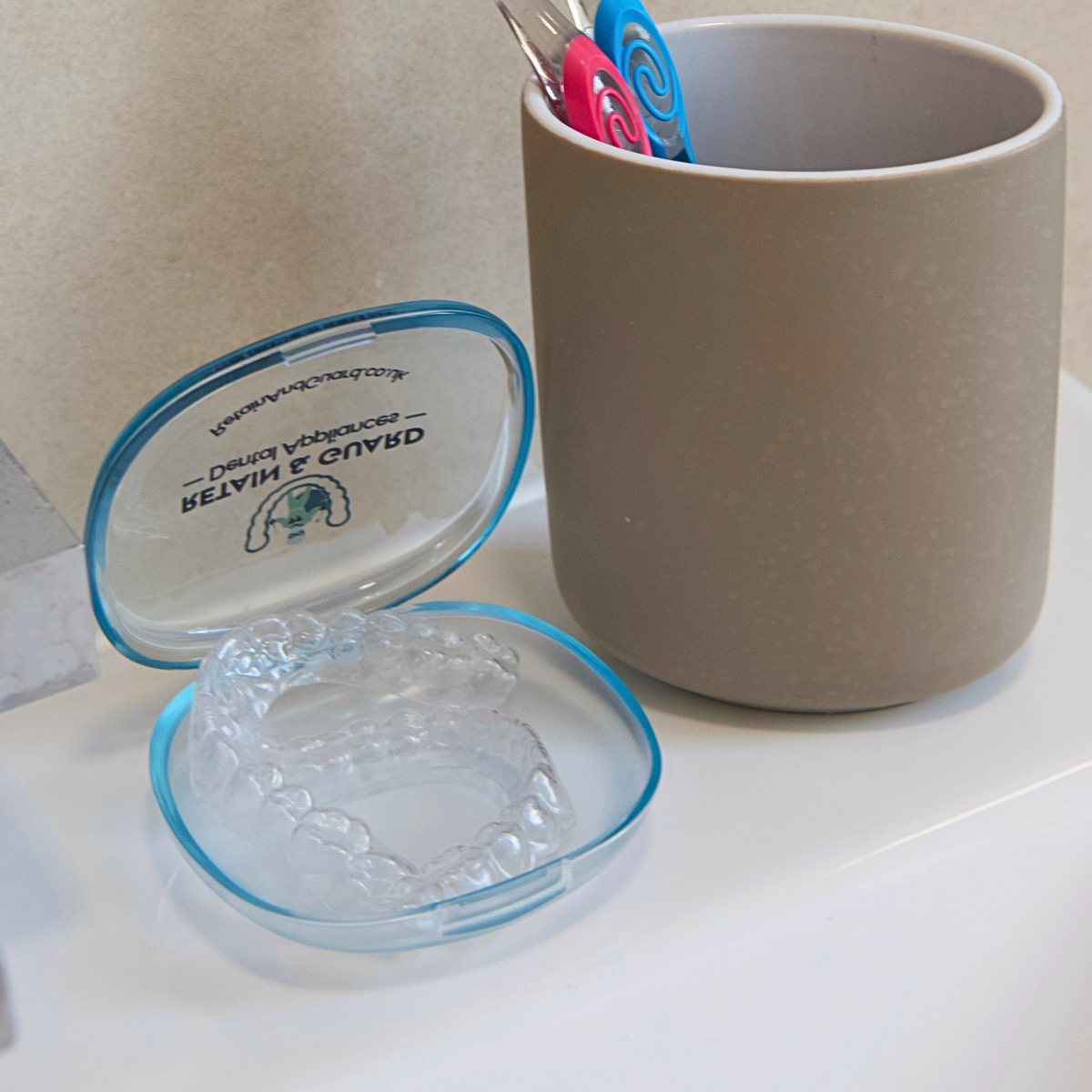 Clear custom-fit retainers stored inside an open protective case
